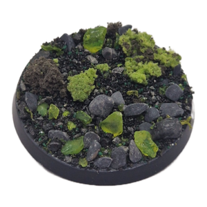 Round miniature base with green and gray textured surface on a white background