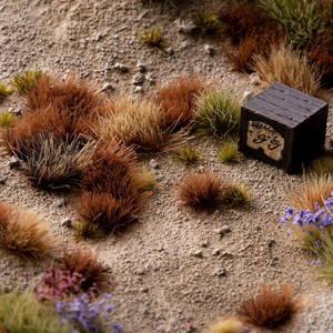 Small wooden block with text on a sandy surface with grass and flowers