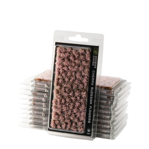 Packaged miniature floral terrain piece labeled 'Cherry Blossom Flowers' by Gamesmiths, showing a textured pink-brown pile of flowers in clear blister packaging, with additional unopened packages stacked behind it on a white background.