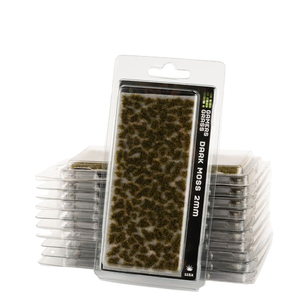 Packaged miniature grass mat labeled 'Grass Grass Dark Moss 2mm' in a clear blister pack, with stacks of similar packs behind it on a white background.