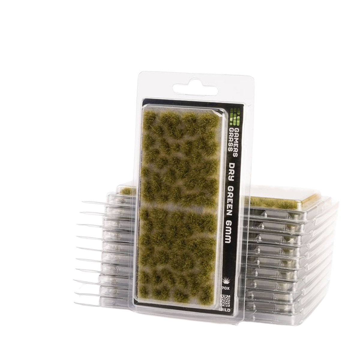Packaged dry green grass miniature foam pieces in a clear blister pack with a white cardboard header, shown with stacks of the same product in the background on a white studio background.