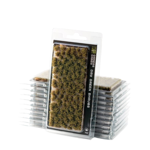 Pack of miniature dry green shrubs in clear plastic blister packaging, with one package standing upright in front of a stack of identical packages on a white background.