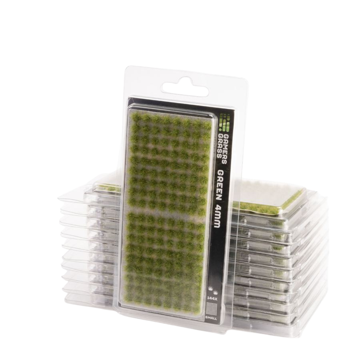 Packaged miniature green grass plugs for tabletop wargaming, shown in a clear blister pack with a black and white label, with stacks of additional packs behind it on a white background.