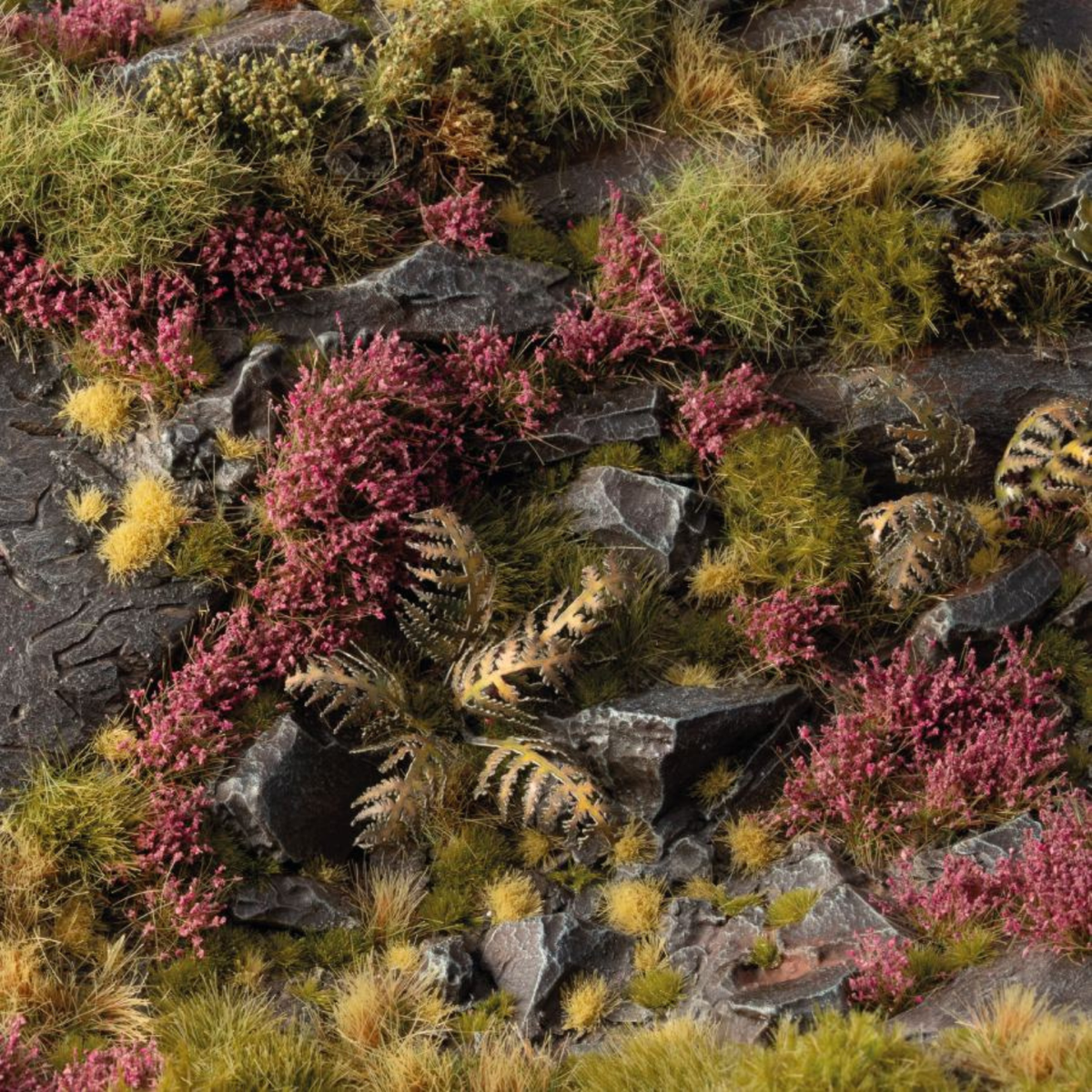 Miniature landscape with pink heather, green grass, and rocks.