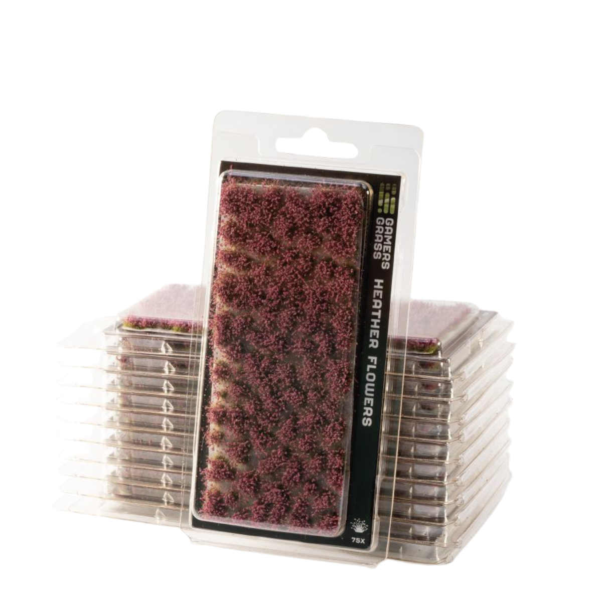 Packaged heathered flowers mini terrain pieces by TPK, featuring a clear blister pack with a black label displaying the textured purple and pink heathered surface, with stacks of individual packaged pieces behind it on a white background.