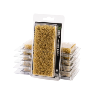 A packaged rectangular natural sponge brush standing in front of several stacked identical packages on a white studio background. The front package shows the text 'SPIKED BRUSH' and 'MADE IN THE USA'.