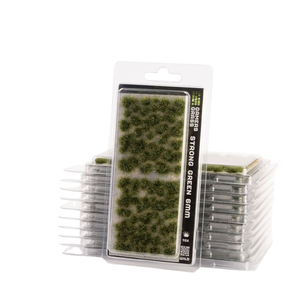 Packaged green grass/turf pieces in a clear plastic blister package, with additional stacks of the same product visible behind it on a white background.